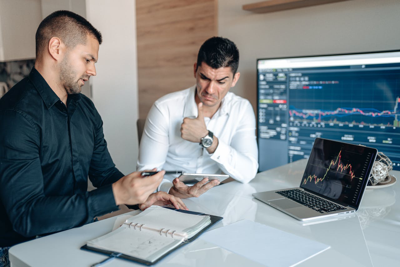 Mastering the First Impression: Your intriguing post title goes here Two professionals discuss data analysis on digital devices in an office setting, focusing on graphs and charts.