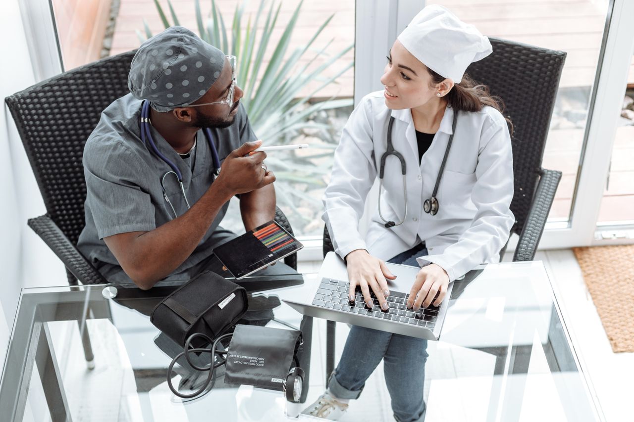 Crafting Captivating Headlines: Your awesome post title goes here Two doctors discussing patient care using a laptop and tablet indoors.