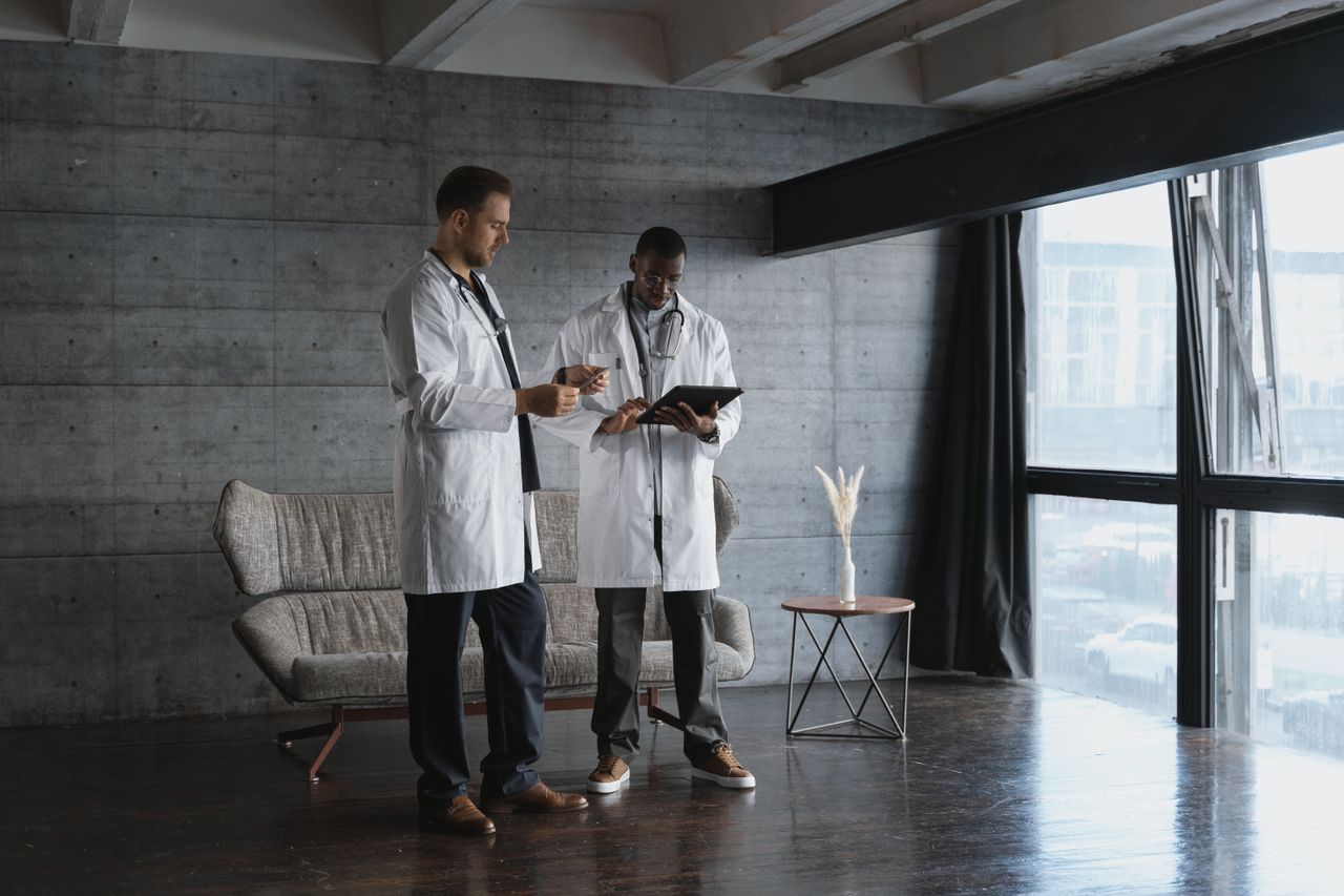 The Art of Drawing Readers In: Your attractive post title goes here Two doctors in an industrial office discuss patient data on a digital tablet.